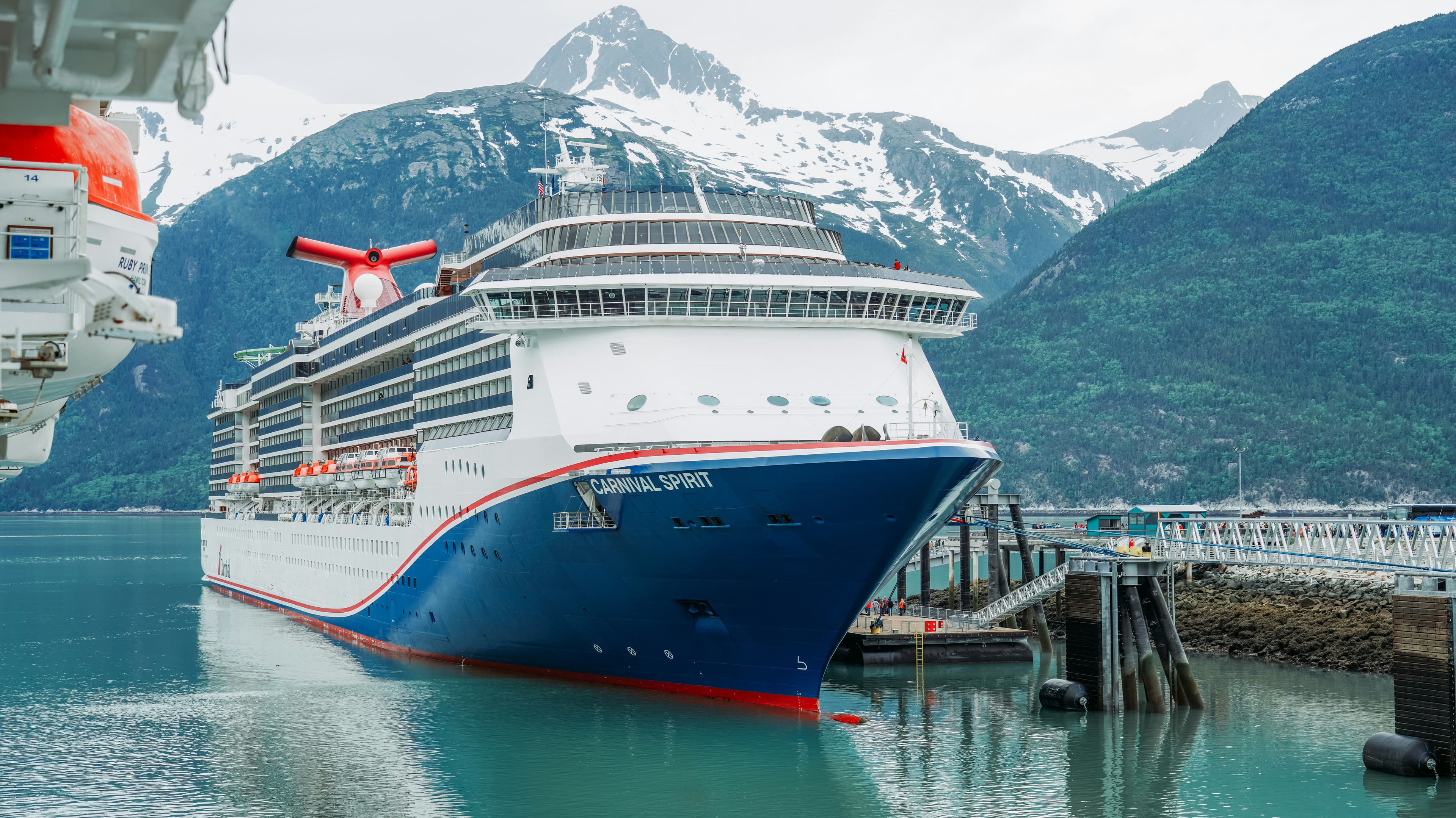 A cruise ship docked in Skagway, Alaska with mountains behind it.